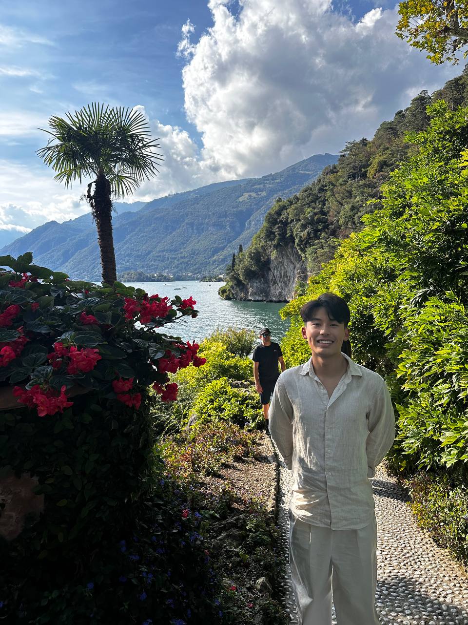 花园小径：红色花墙、棕榈与湖畔山崖。