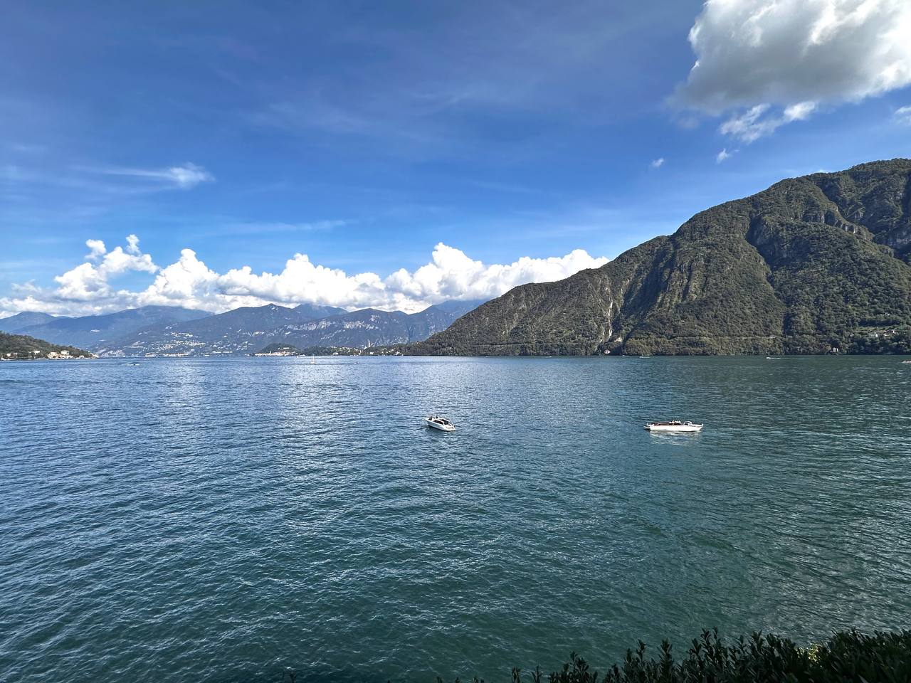 从渡轮上看 Lake Como：湖面、远山与航行的小船。