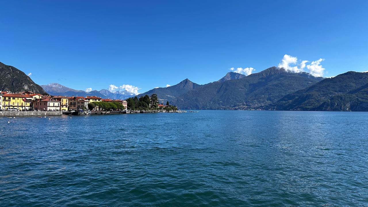 湖畔全景：屋顶、树影与对岸群山。